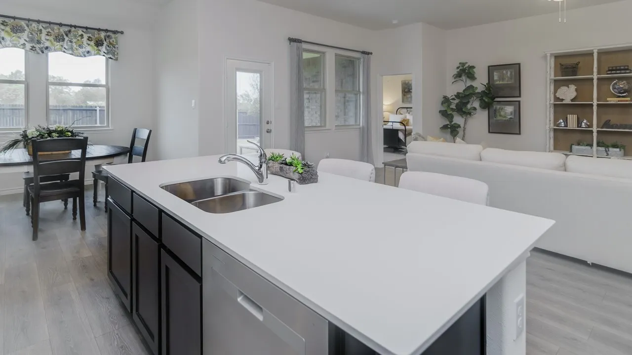 Kitchen island with a double stainless steel sink, light-toned countertop, and dark cabinetry