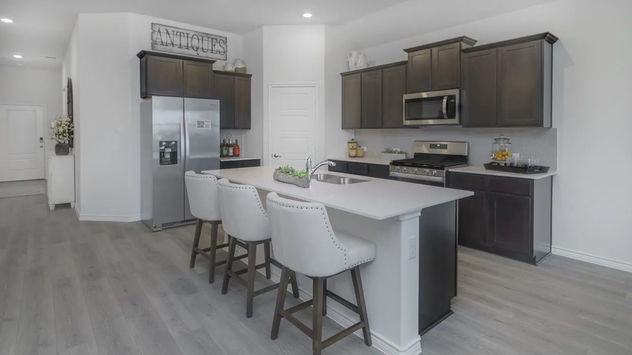 Kitchen with dark wood-finish cabinetry, stainless steel appliances, a white countertop island with seating, and wood-finish flooring
