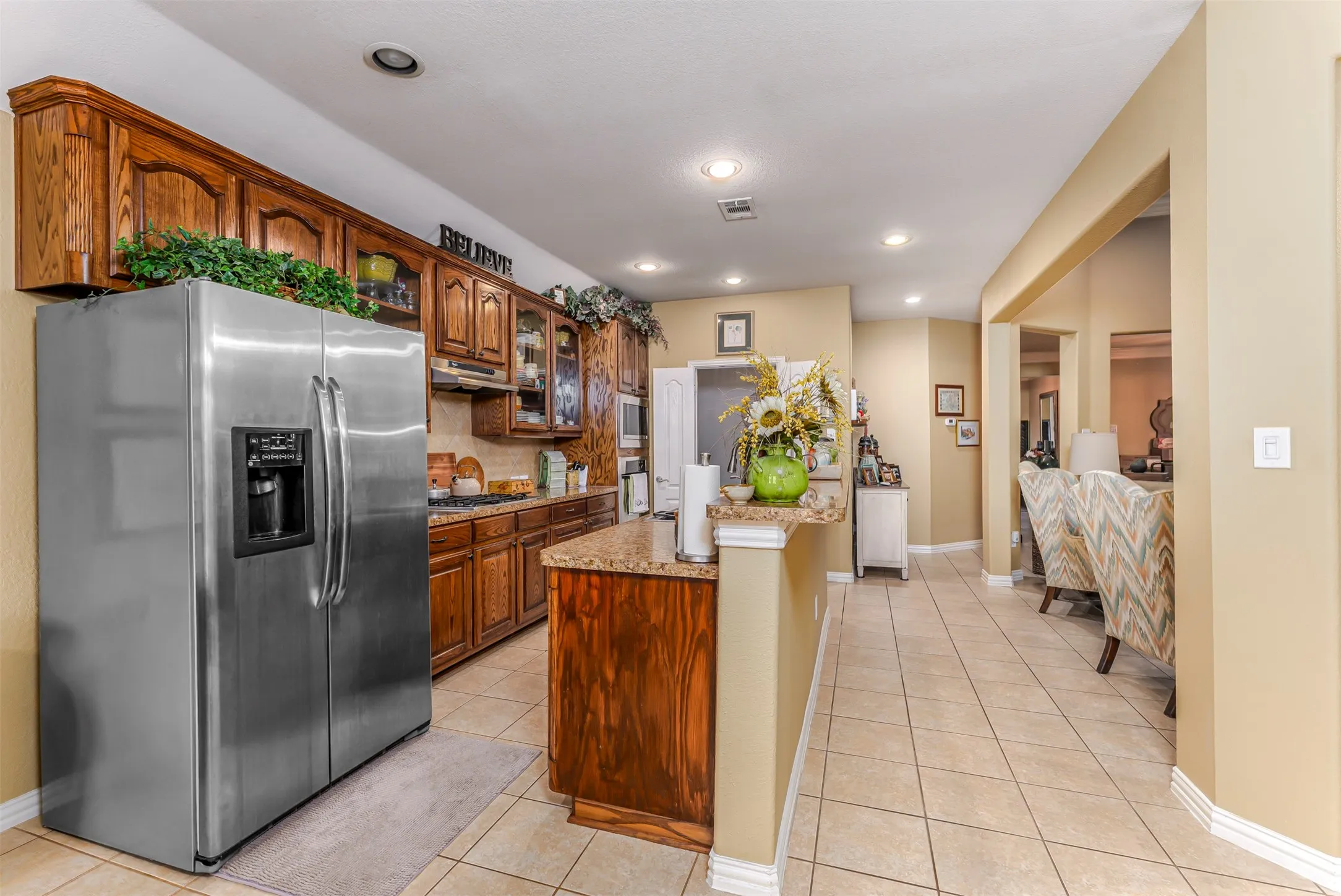 Kitchen featuring wood cabinetry, stainless steel appliances, granite countertops, and tile flooring