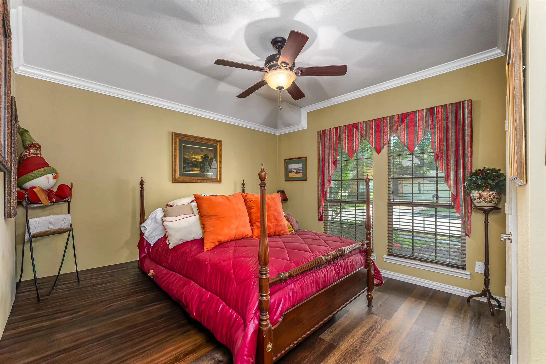 Tray ceiling with crown molding, wood-finish flooring, and a ceiling fan with integrated lighting