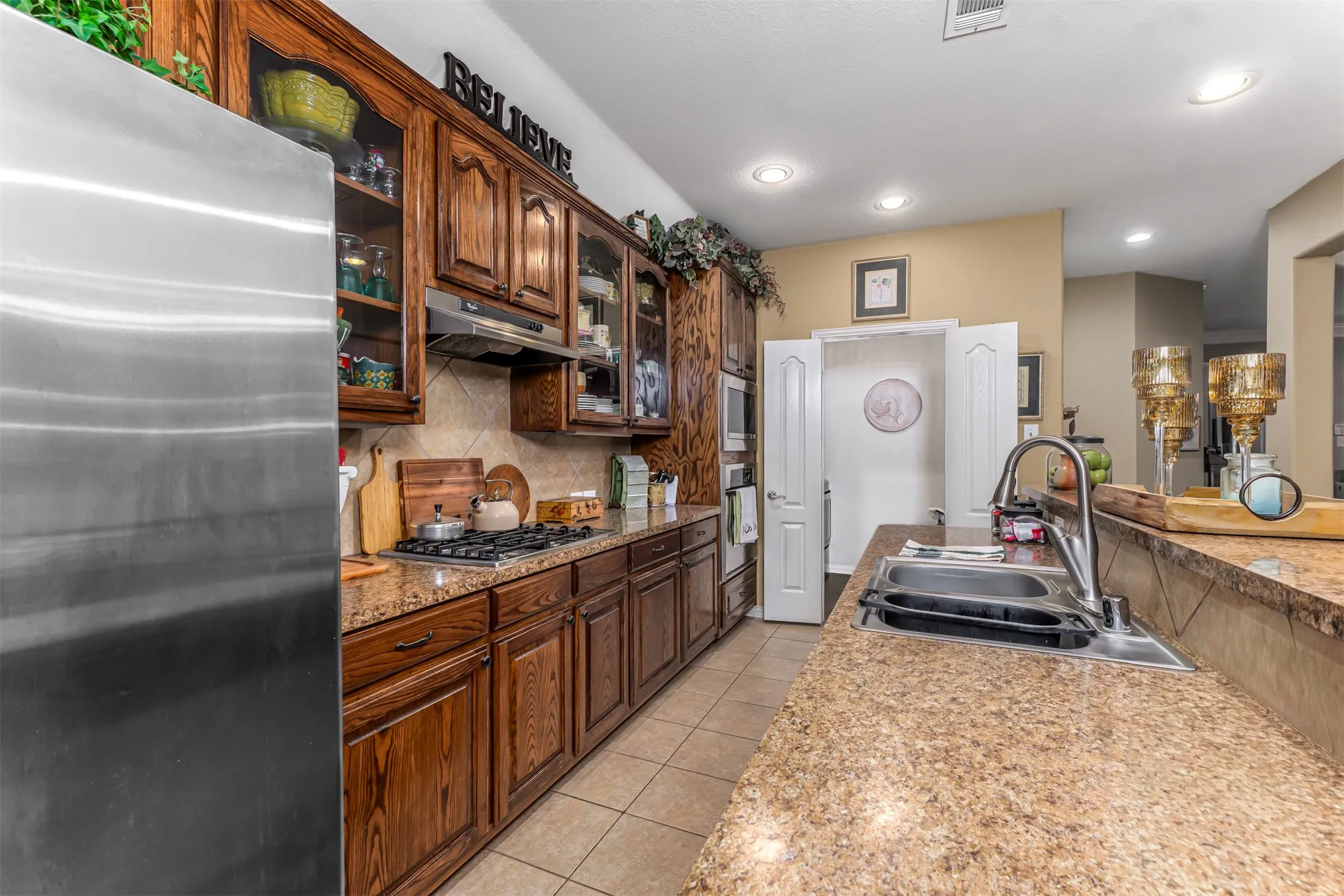 Kitchen featuring wood cabinetry, stainless steel appliances, a gas cooktop, stone countertops, and recessed lighting