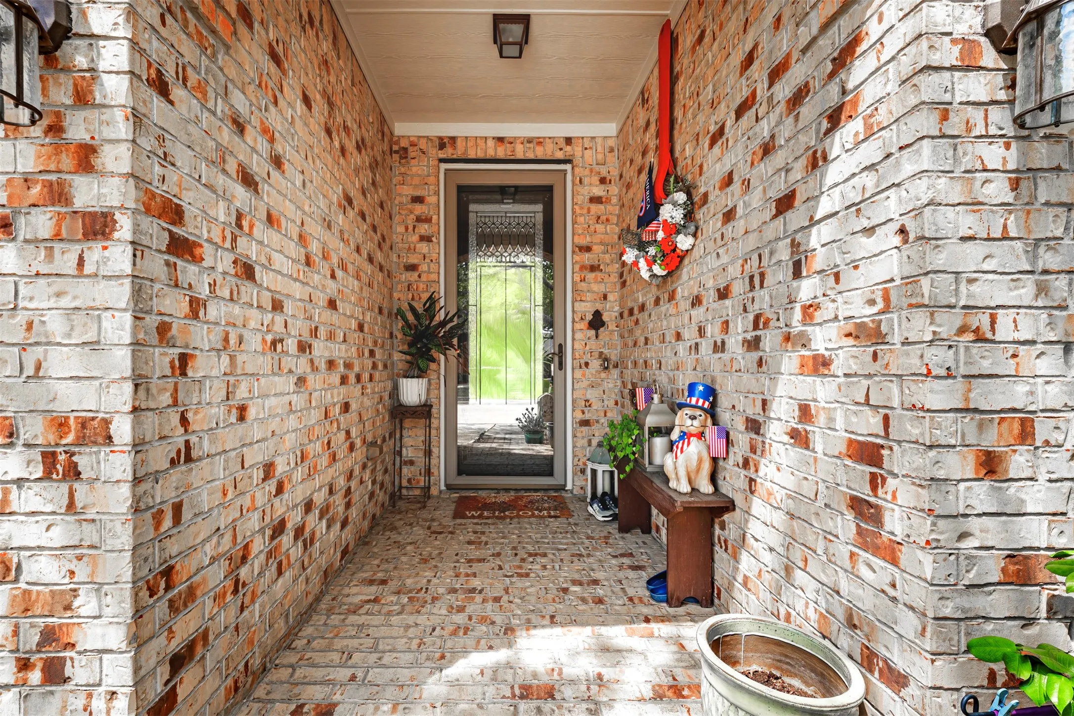 Brick facade with a covered entry, overhead lighting, and a glass-paneled entry door
