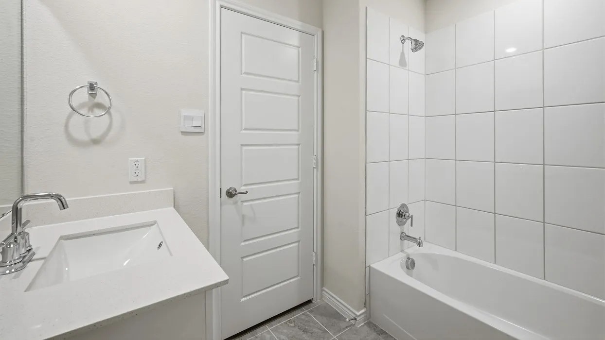 White tile shower surround, integrated bathtub, chrome showerhead, and chrome tub filler