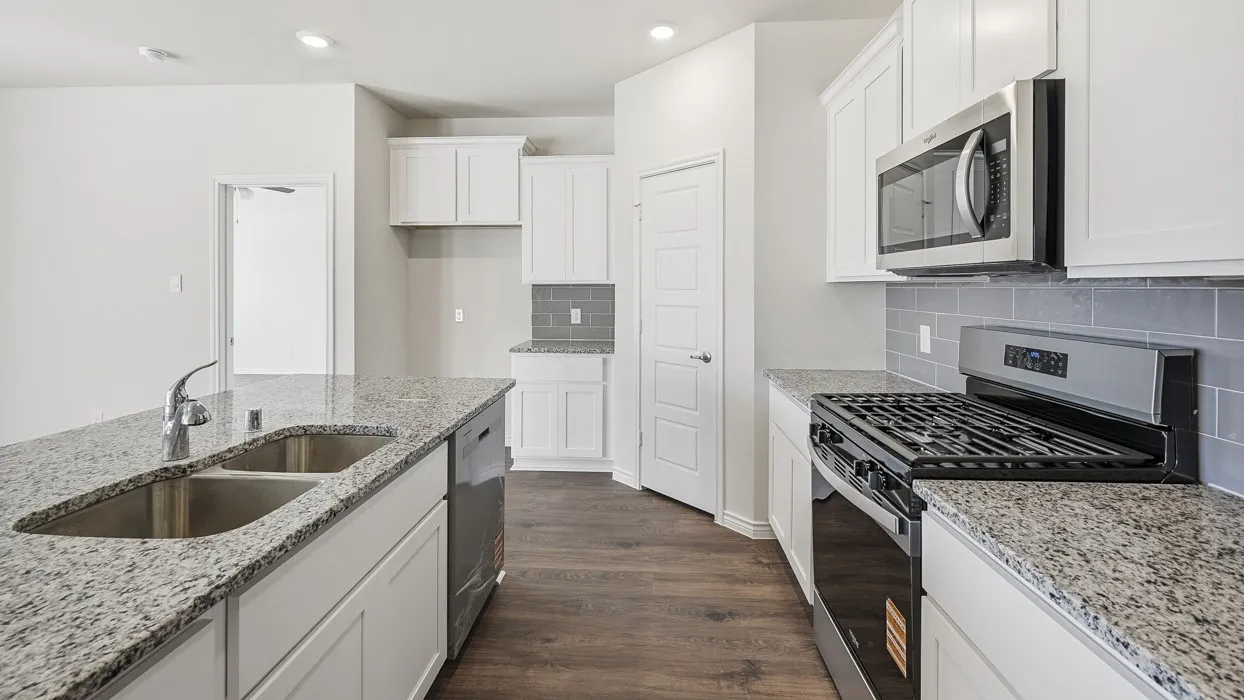 Kitchen featuring an island with a double basin sink, stainless steel appliances, white cabinetry, granite countertops, and wood-finish flooring