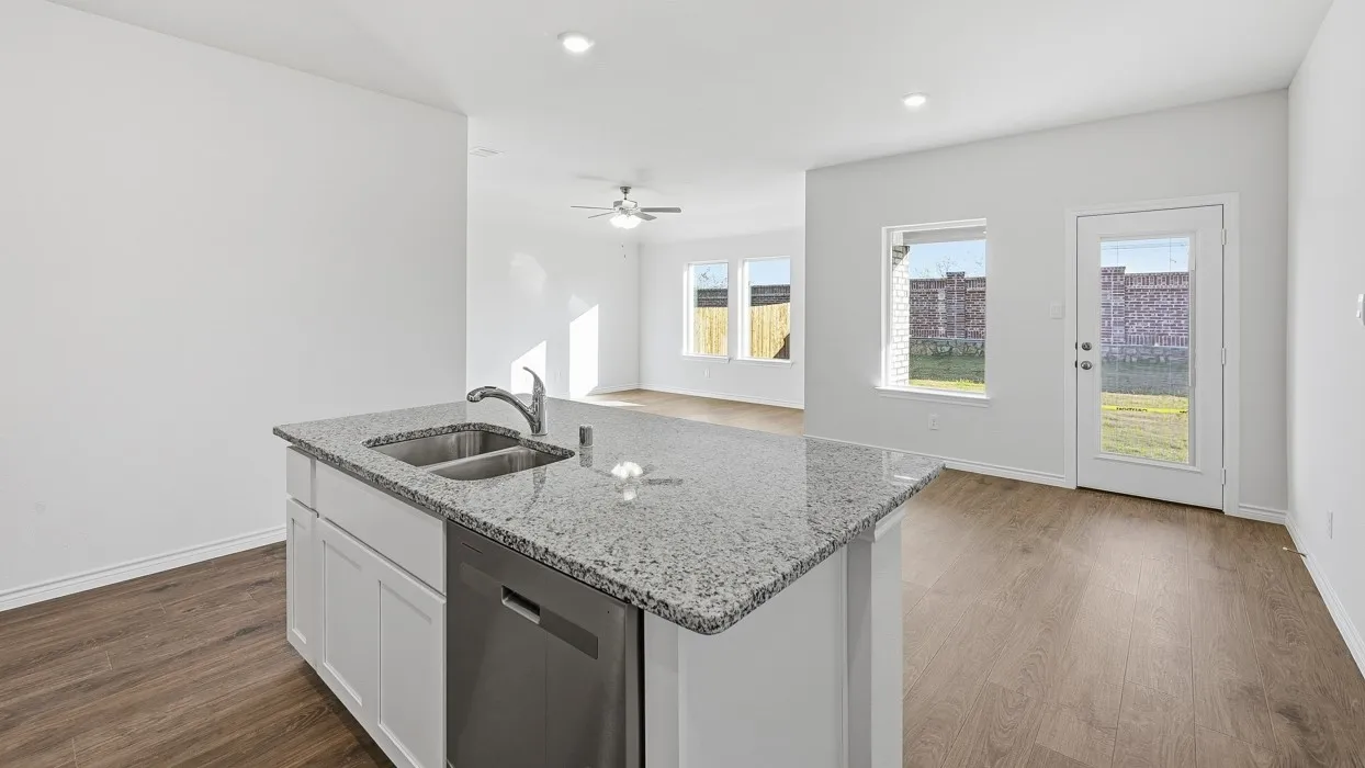 Kitchen island with granite countertop, double basin sink, and integrated dishwasher