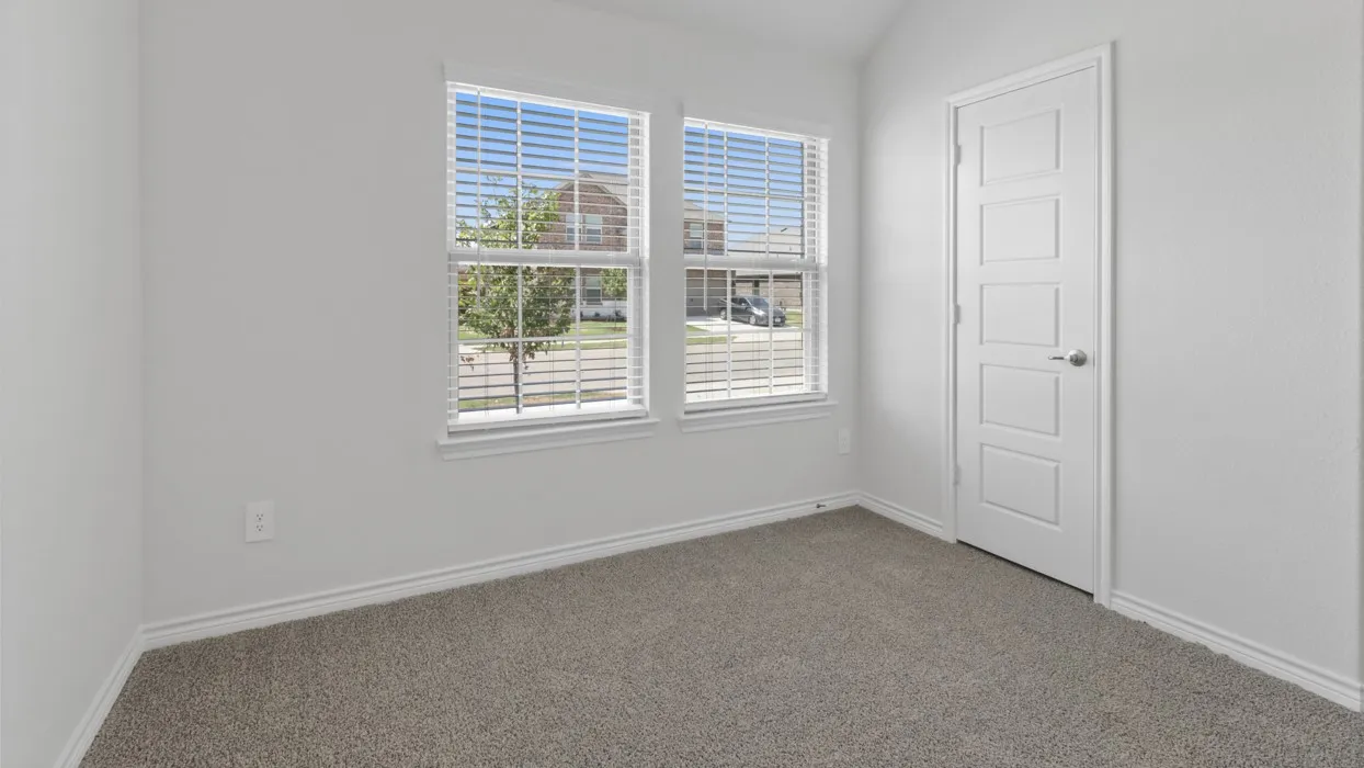 Dual windows with blinds, gray carpeting, neutral wall paint, and a paneled interior door