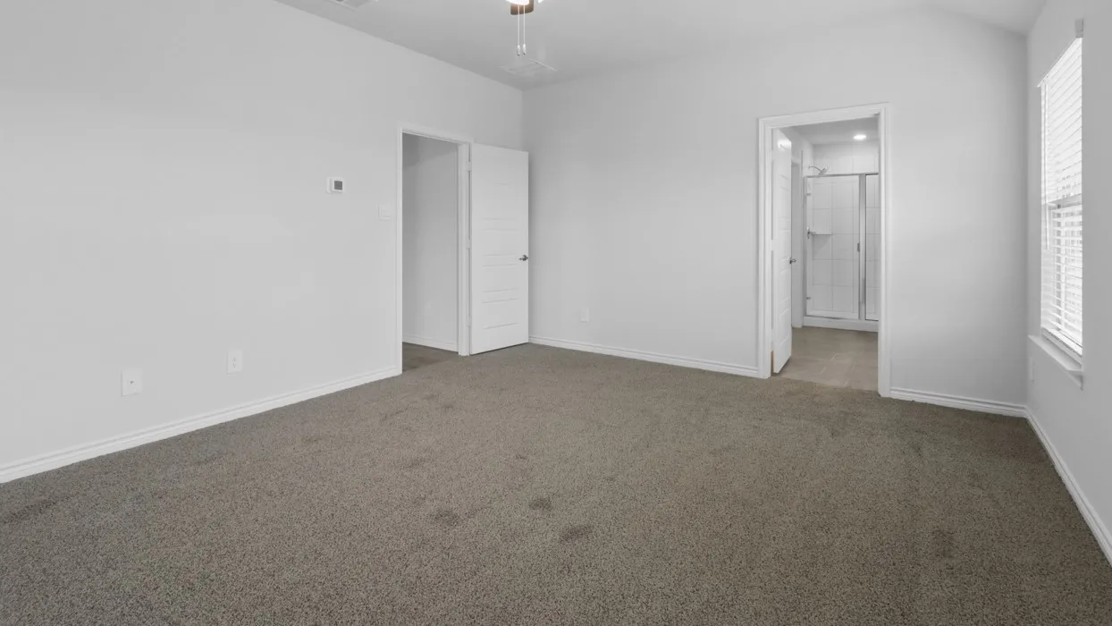Gray carpeted flooring, white interior doors, vaulted ceiling, window with blinds, and an attached shower enclosure
