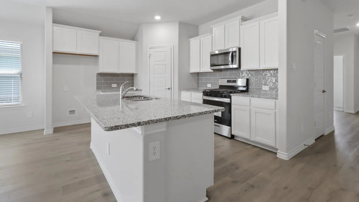 Modern kitchen featuring white cabinetry, stainless steel appliances including a gas range and microwave, granite-style countertops, a large center island with seating space, subway tile backsplash, and wood-finish flooring throughout the open layout