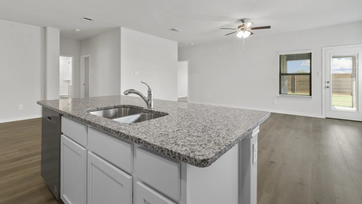 Kitchen island with a stainless steel sink and granite countertop, featuring white cabinetry and an integrated dishwasher