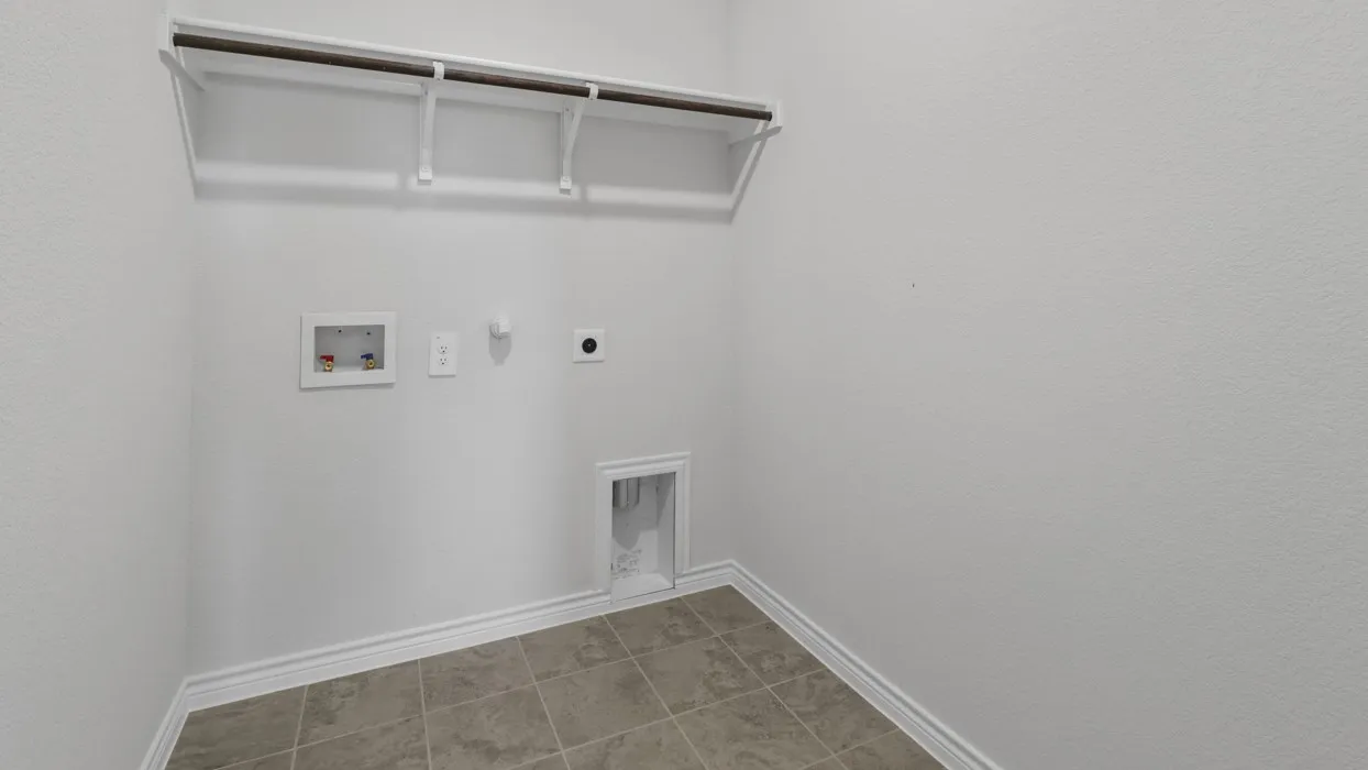 Wall-mounted shelving with a hanging rod, tile flooring, and utility hookups