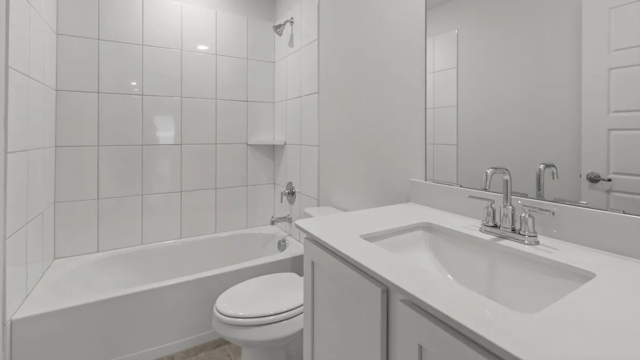 White tile shower surround, integrated bathtub, and a vanity with a white countertop