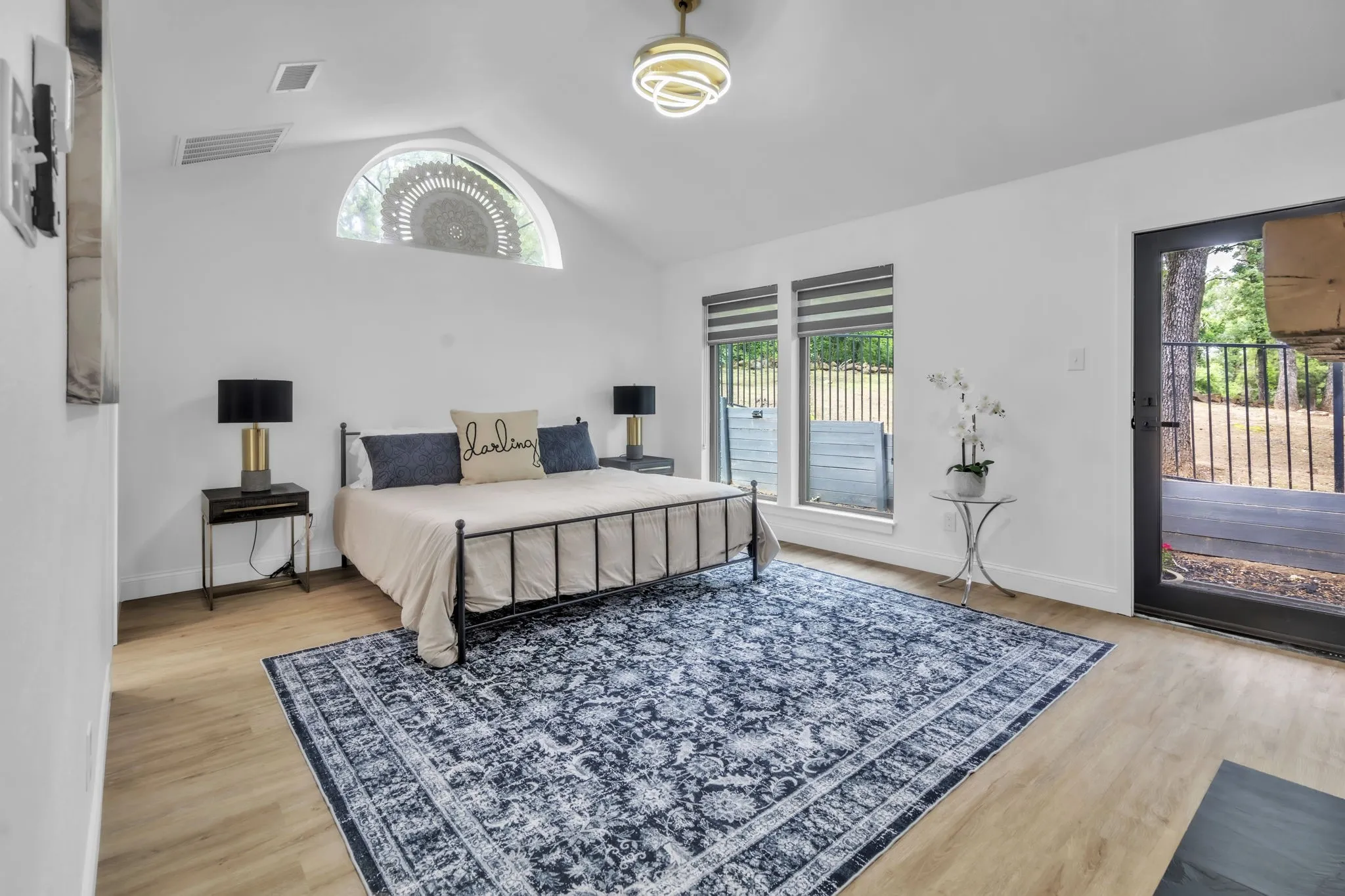 Primary bedroom overlooking the trees in the backyard and sparkling pool.