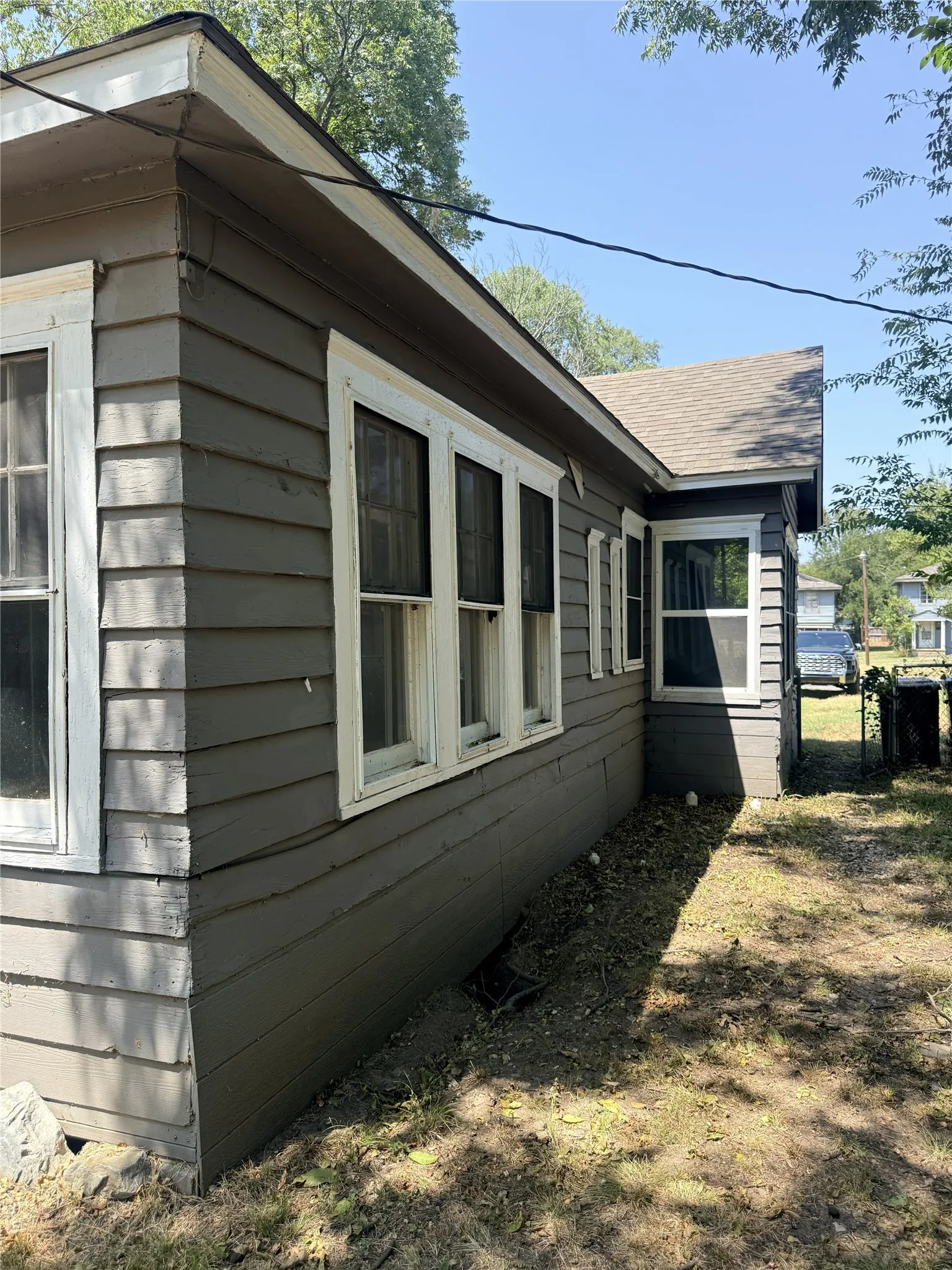 Shingle roofline, horizontal siding exterior, multiple window openings with white trim