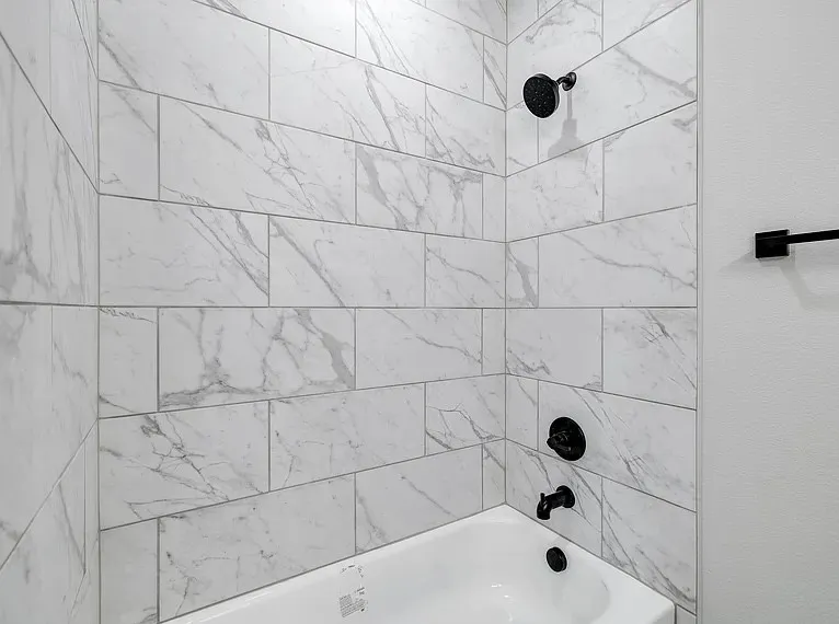 Bathtub with subway tile surround, matte black shower head, and coordinating faucet