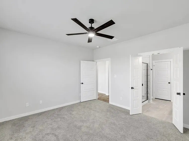 Spacious room with gray carpet flooring and a ceiling fan