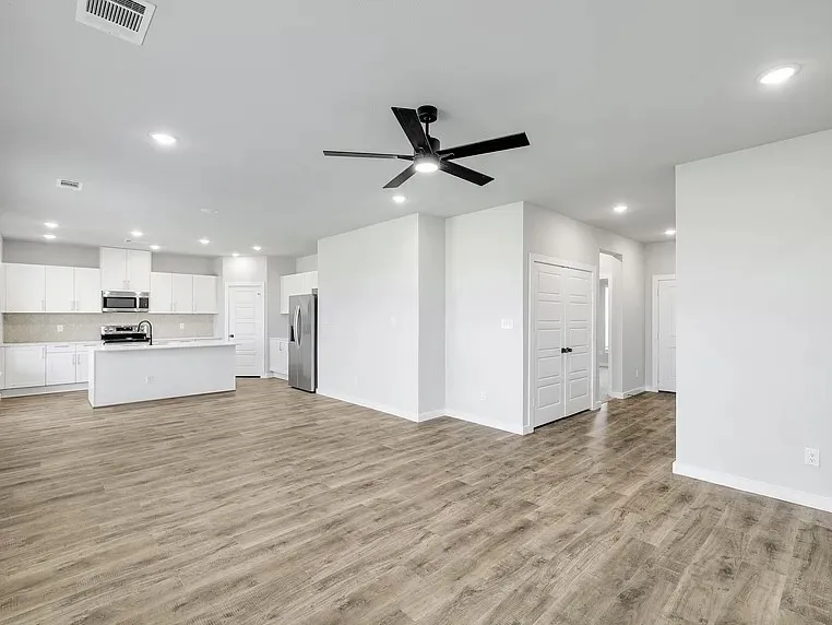 Open-concept layout with wood-finish flooring, recessed lighting, and a contemporary ceiling fan