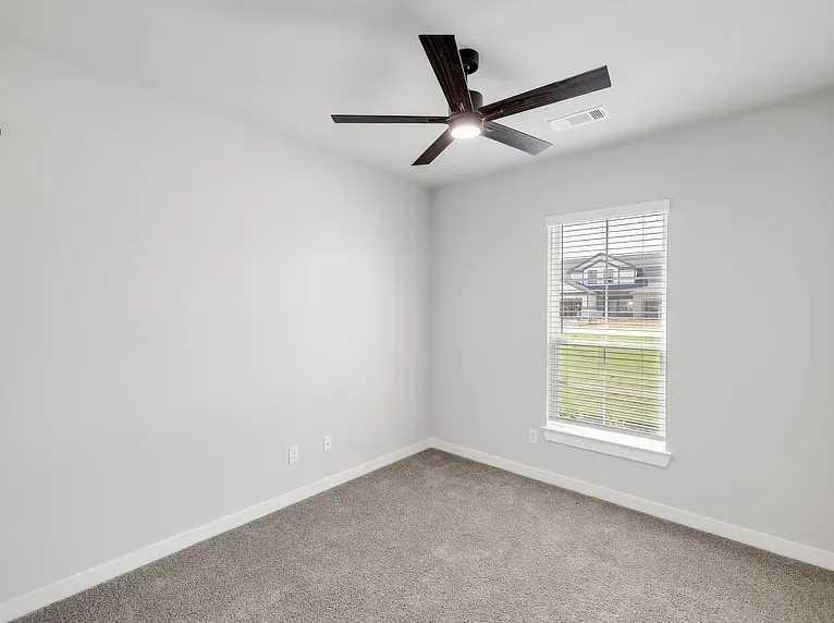 Neutral gray walls, gray carpet, white trim, a single window with blinds, and a ceiling fan with integrated lighting