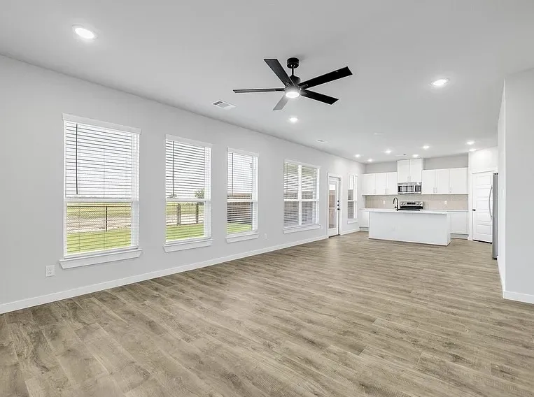 Open-concept living space with wood-finish flooring, recessed lighting, and a contemporary ceiling fan