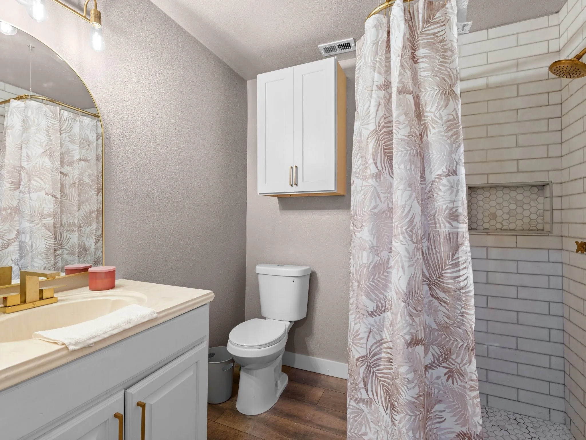 Bathroom featuring a built-in shower niche, hexagon tile shower floor, subway tile shower surround, and a vanity with a rectangular undermount sink
