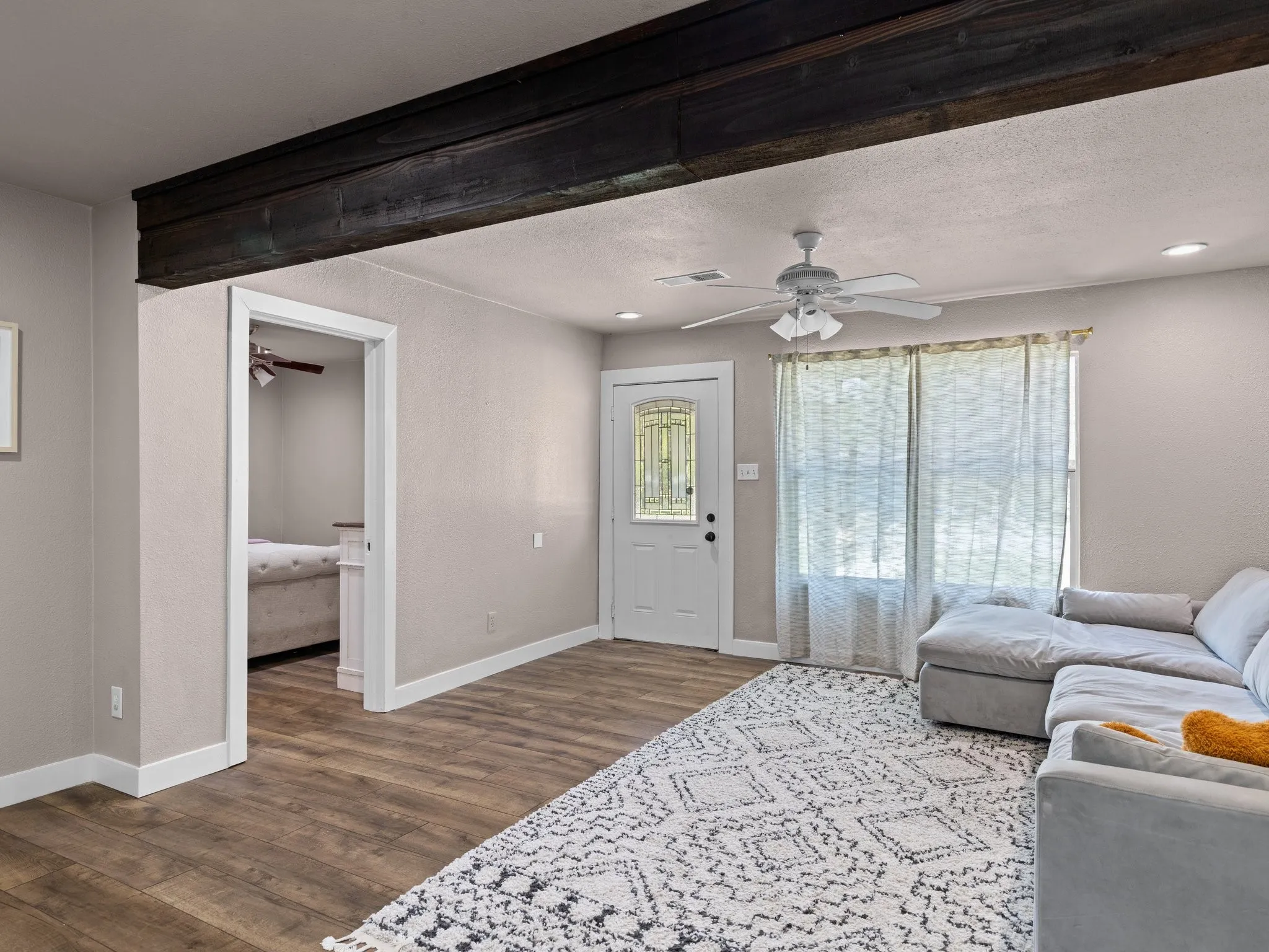 Wood-finish flooring, exposed ceiling beam, ceiling fan, transom window, recessed lighting