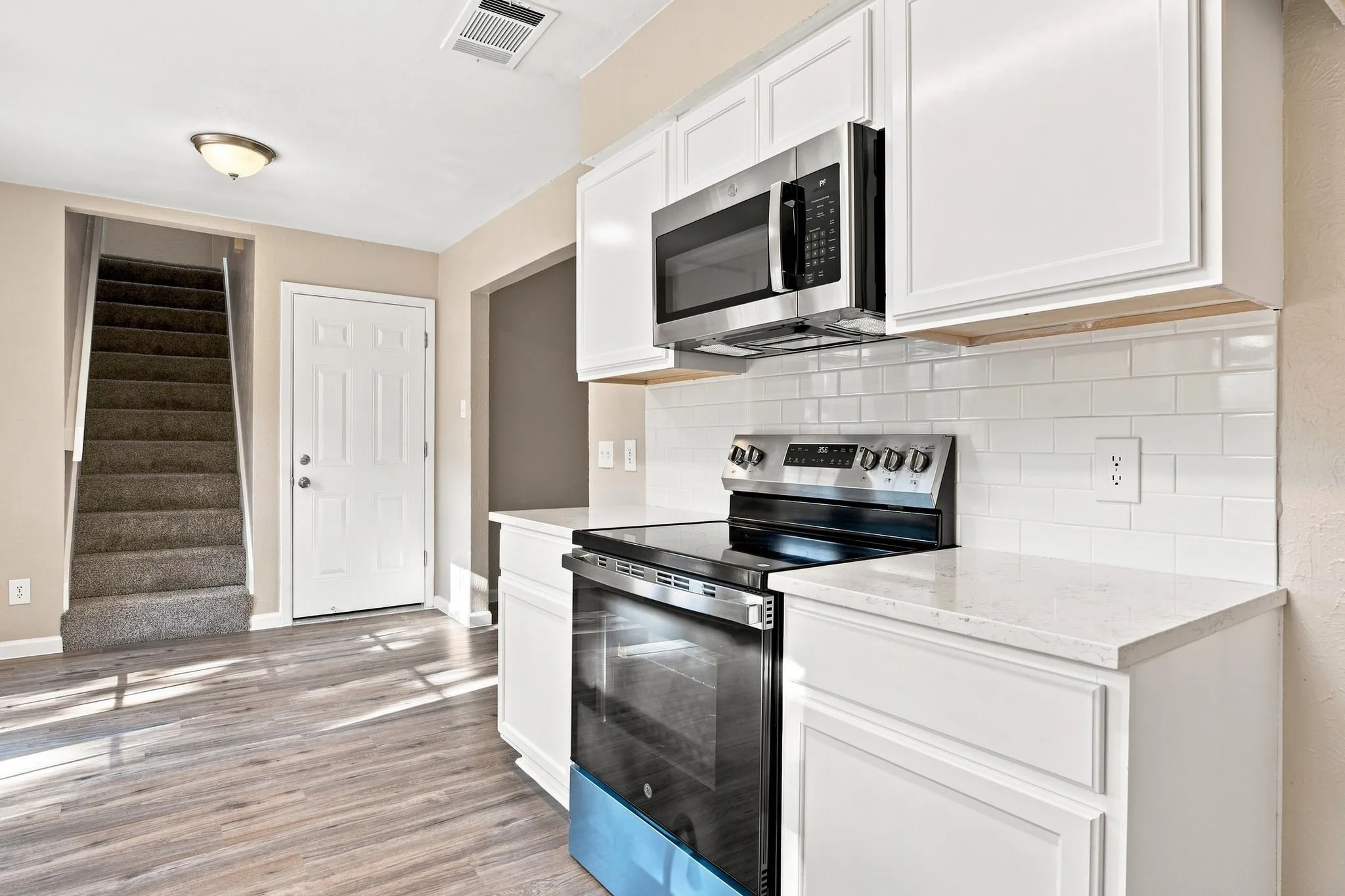 White vanity with a stone-finish countertop, brushed nickel faucet, and wood-finish flooring