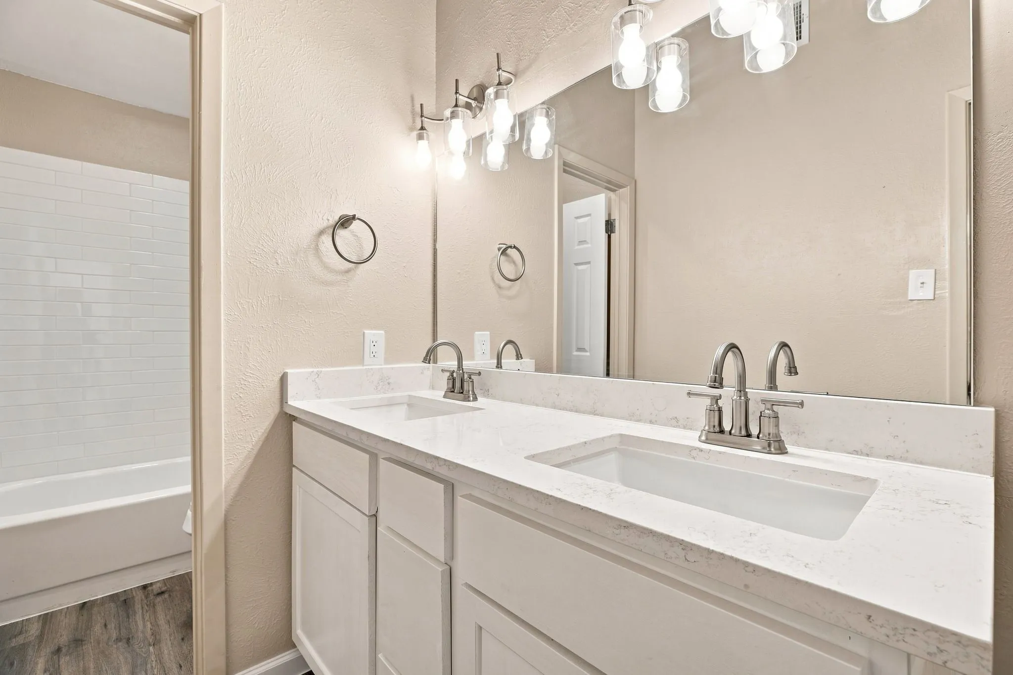 Dual vanity with white cabinetry and integrated sinks, brushed nickel fixtures, and overhead lighting