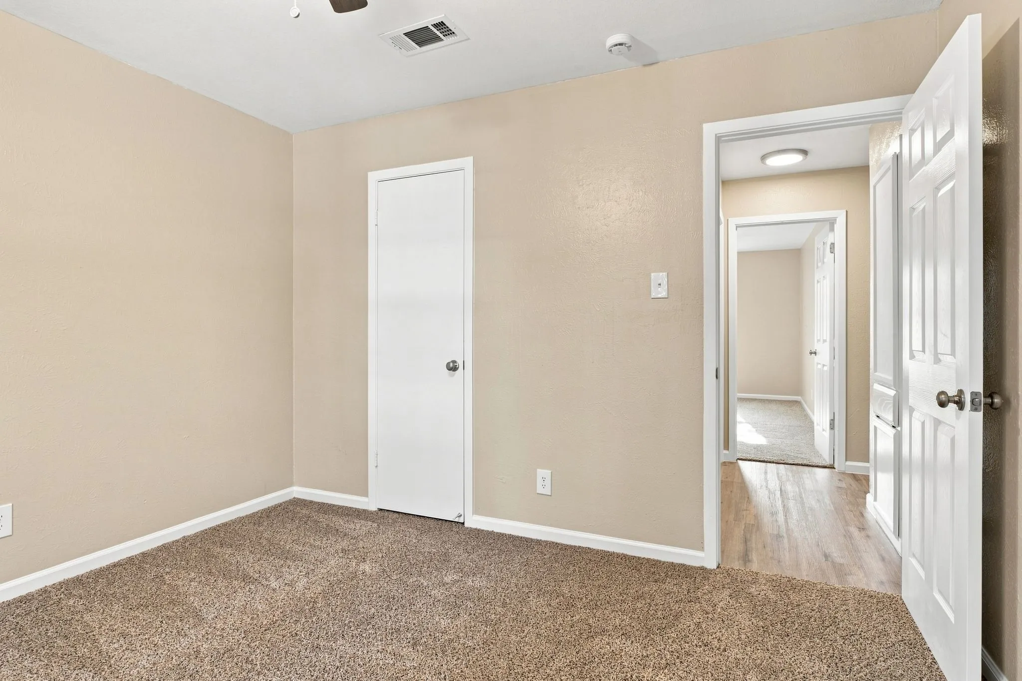 Neutral tone painted walls with gray carpet flooring and a ceiling fan