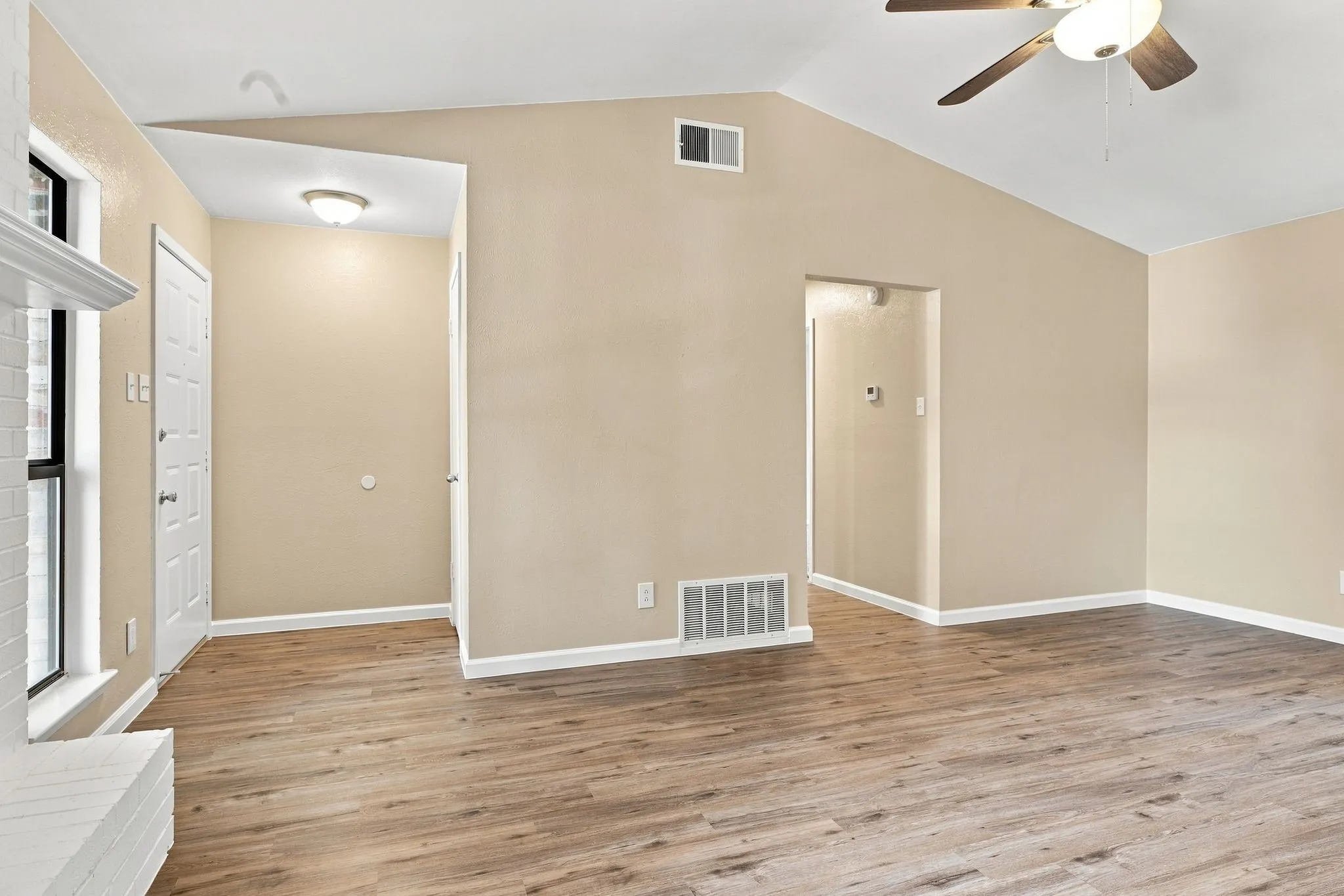 White shaker-style cabinetry, stainless steel appliances, light-toned countertops, white subway tile backsplash, and wood-finish flooring