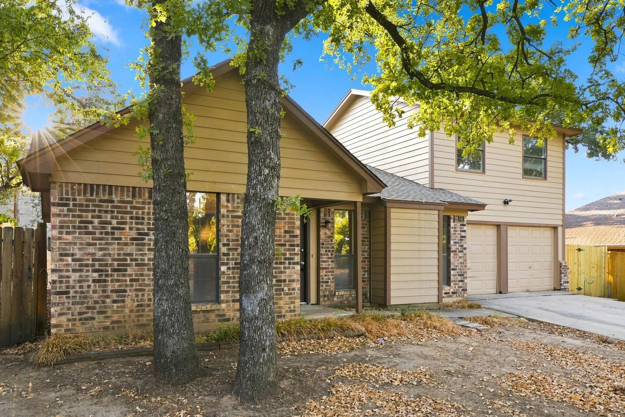 Two-story residence featuring a two-car garage, brick accents, and horizontal siding