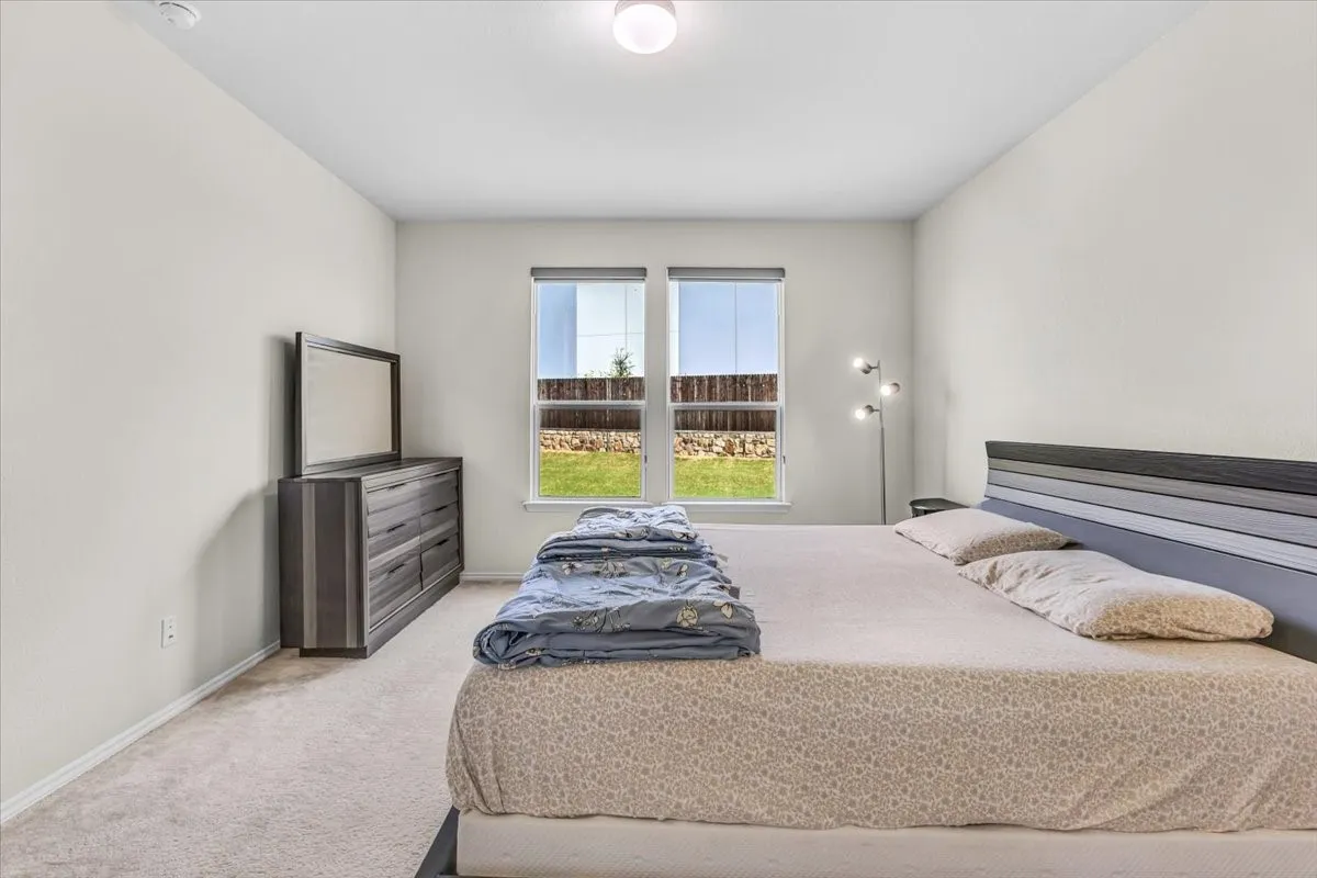 Recessed ceiling light, two windows with roller shades, and carpeted flooring