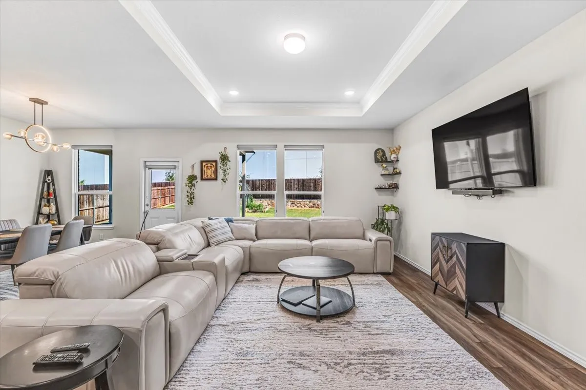 Tray ceiling with recessed lighting, wood-finish flooring, and multiple windows