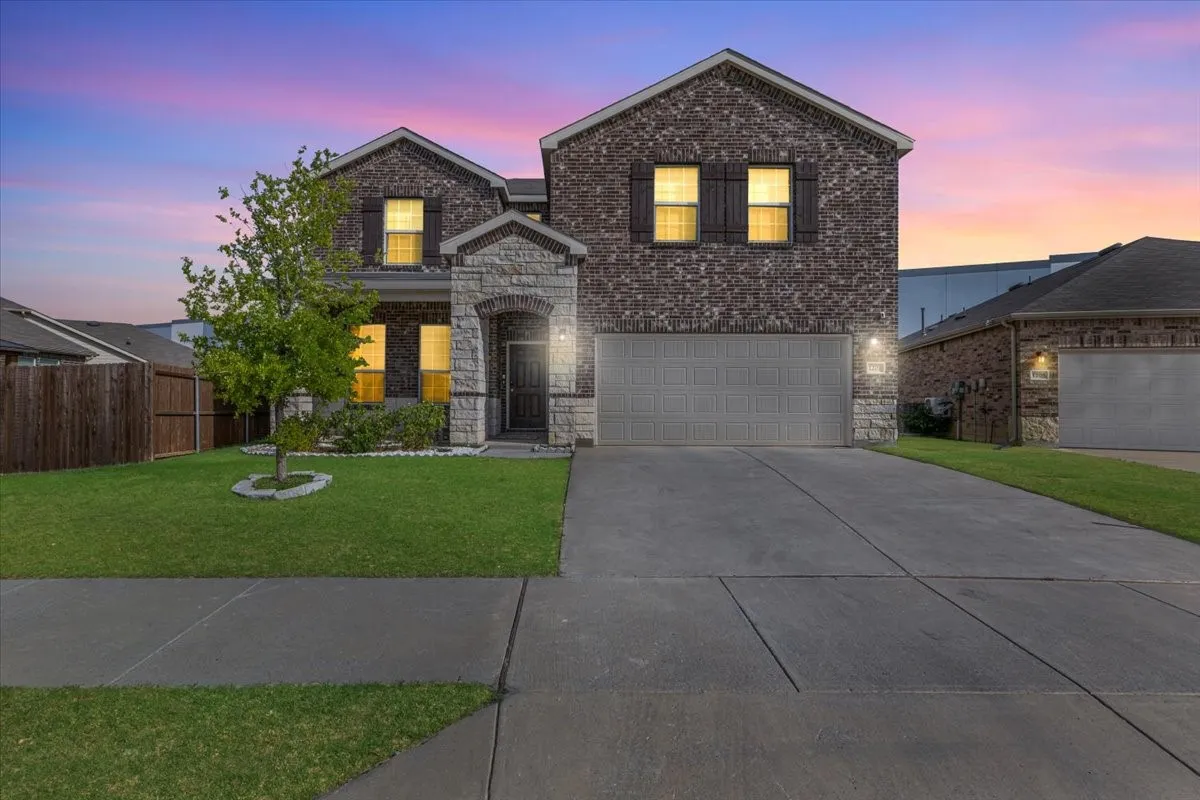 Two-story exterior with brick and stone accents, an attached two-car garage, and a concrete driveway