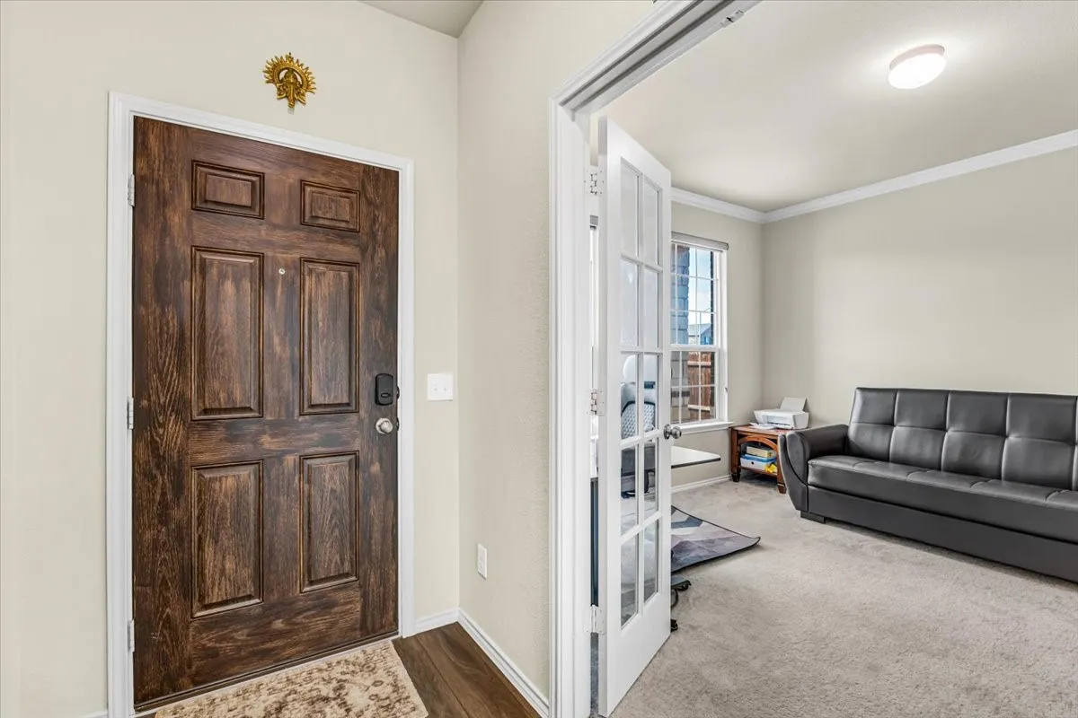 Entryway featuring a paneled wood-finish door with smart lock hardware and wood-finish flooring