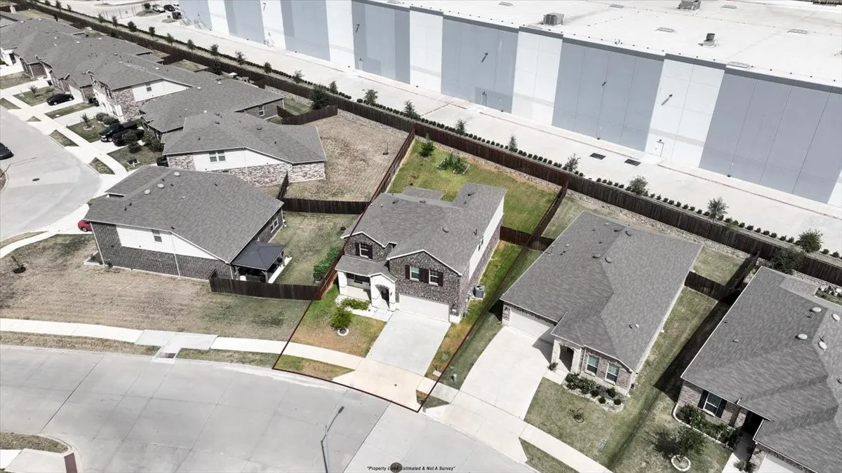 Aerial perspective showcasing the property's perimeter, a covered patio, and the front yard with a paved driveway