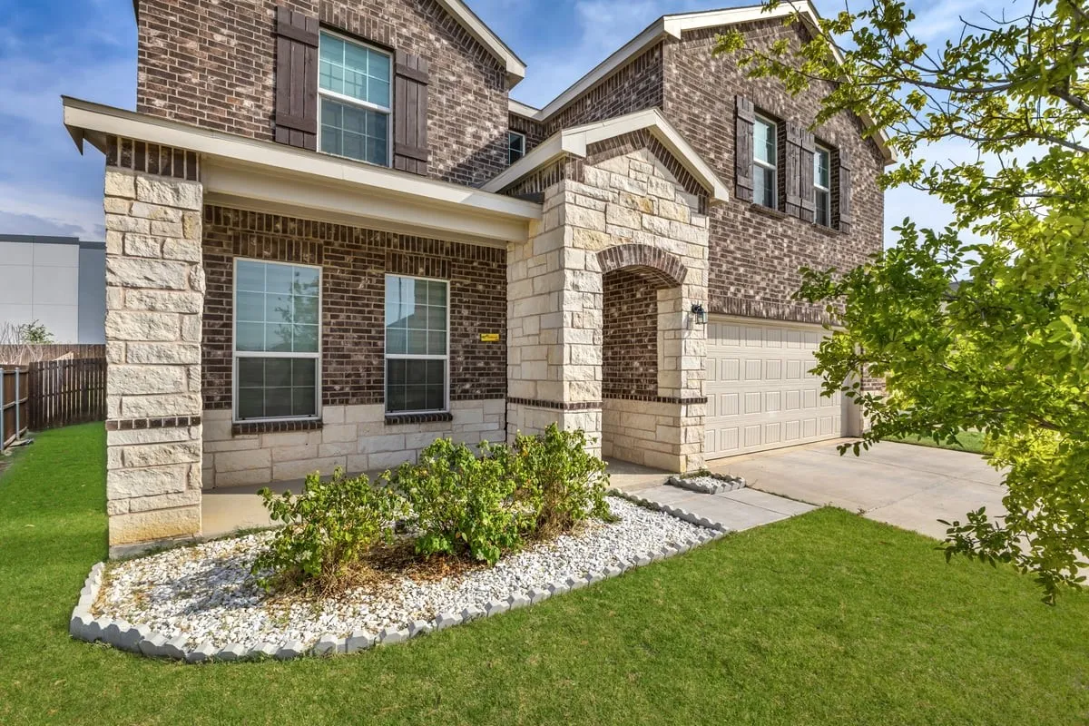 Brick and stone exterior featuring an arched entry, prominent front columns, and a two-car garage