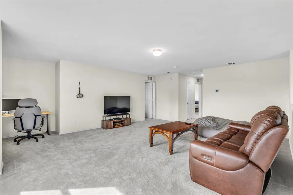 Neutral wall paint, light-colored carpeting, recessed ceiling lighting, and a well-defined alcove