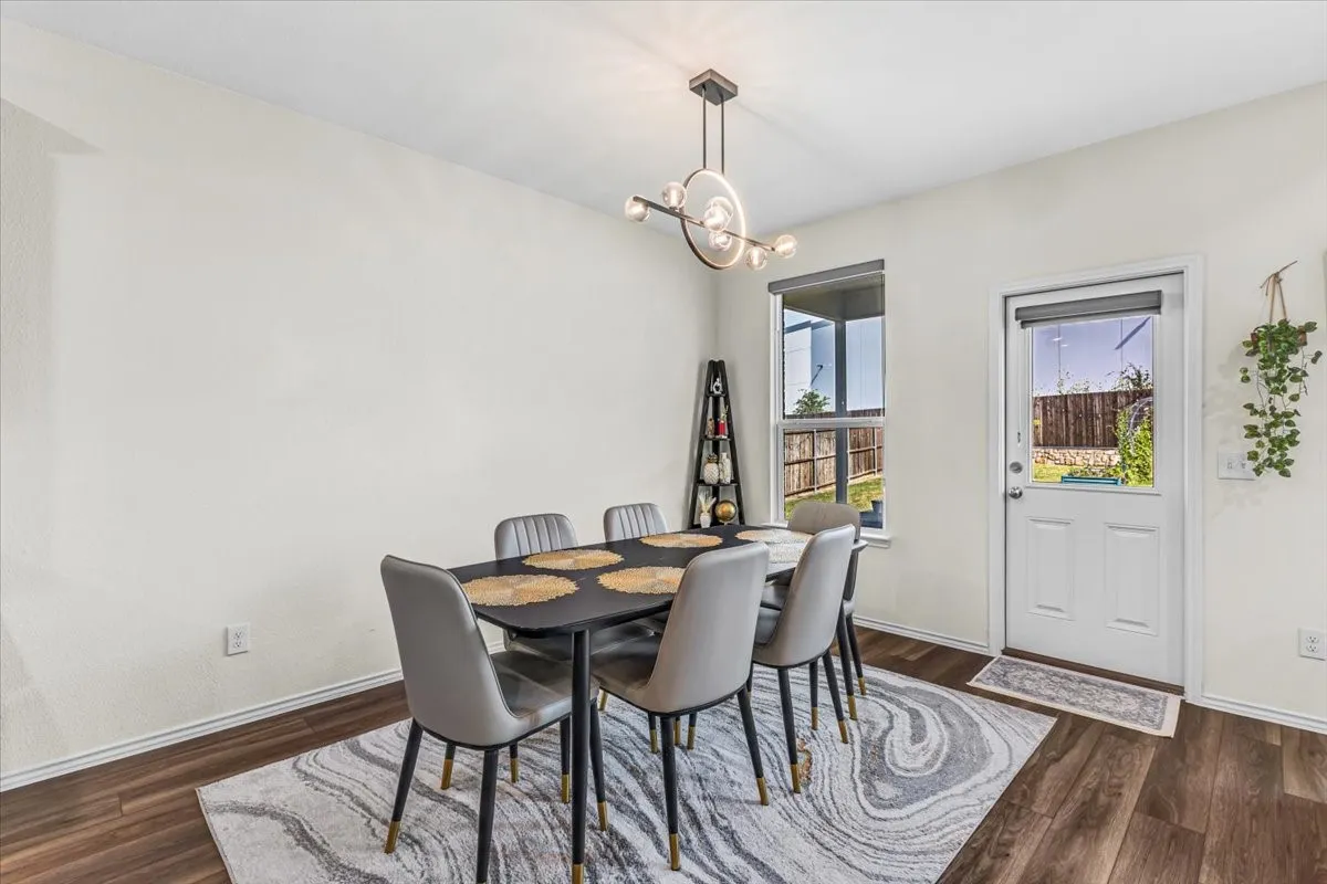 Wood-finish flooring, modern ceiling light fixture, white walls, and a glass-paned door