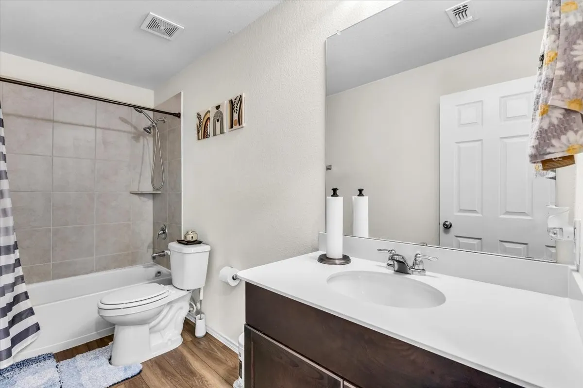 White vanity with integrated sink, chrome faucet, and expansive mirror