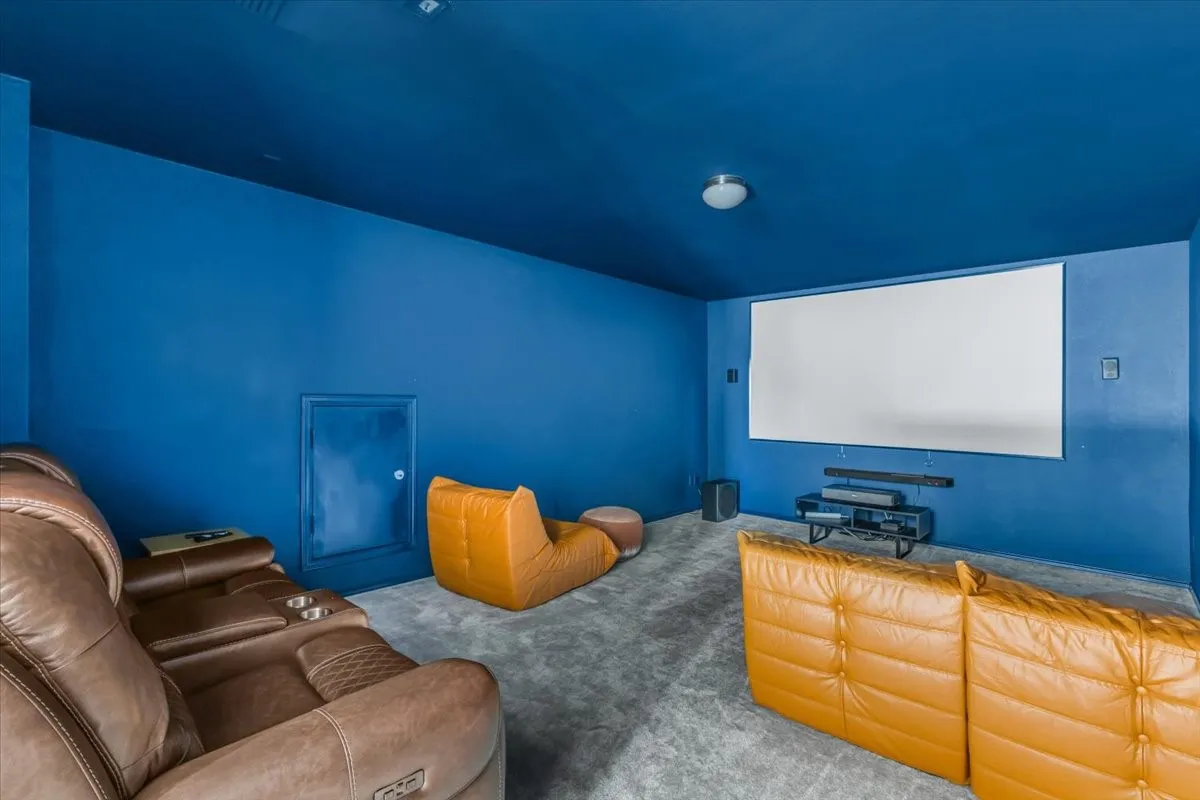 Dedicated media room with a large projection screen, dark blue walls, and grey carpeting