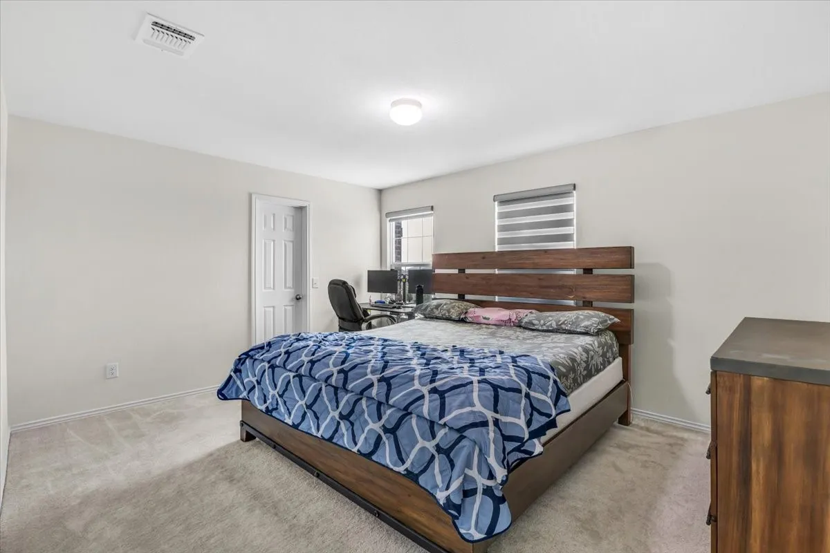 Carpeted bedroom with neutral walls, recessed lighting, and windows featuring horizontal blinds