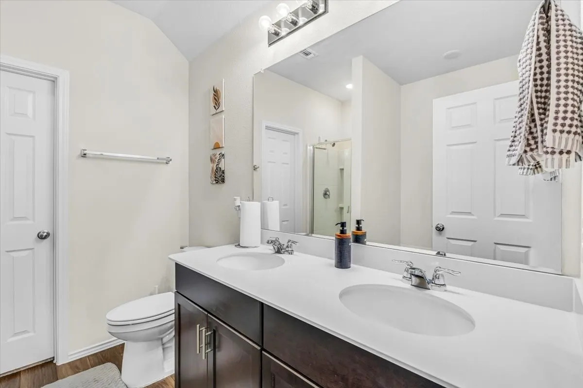Dual vanity with integrated sinks, dark wood-finish cabinetry, and chrome fixtures