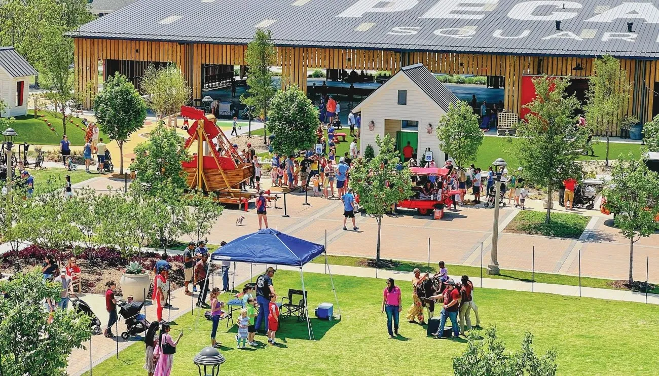 Expansive public square featuring a large wooden structure, paved walkways, and dedicated green spaces