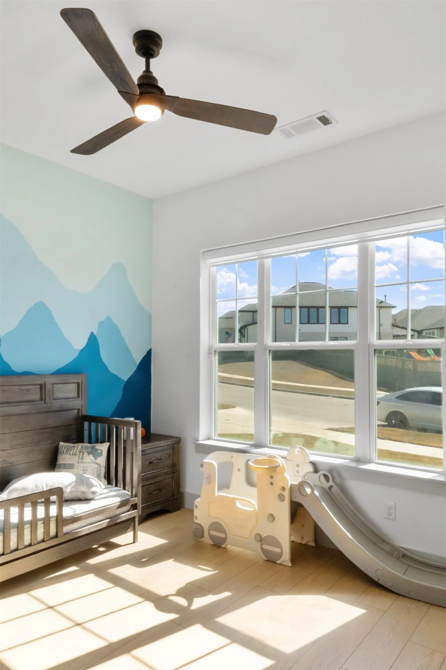 Recessed lighting, wood-finish flooring, ceiling fan with integrated lighting, expansive window, painted accent wall