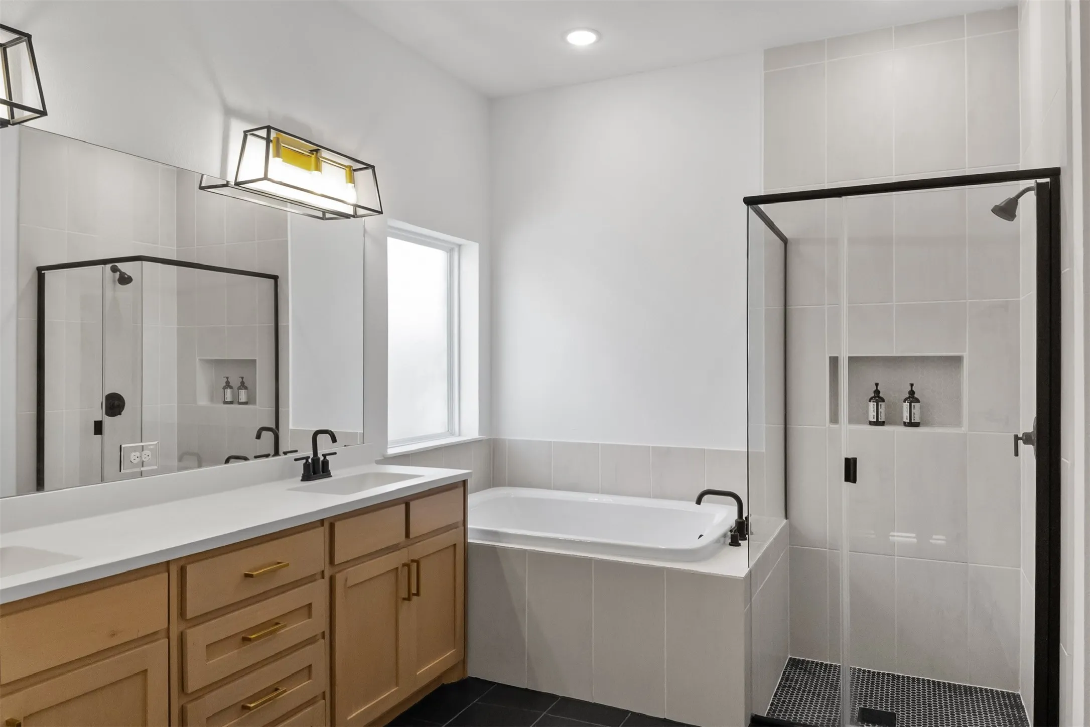 Dual vanity with wood-finish cabinetry, white countertop, and matte black fixtures