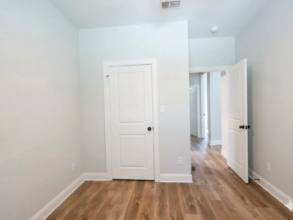 Wood-finish flooring, white doors with black hardware, and crisp white trim
