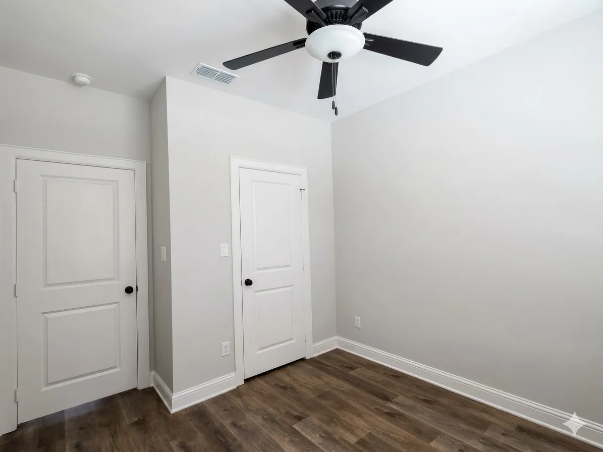 Wood-finish flooring, white trim, and a ceiling fan with light fixture