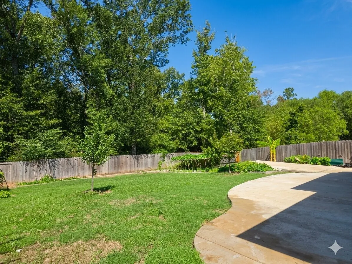 Expansive backyard featuring a curved concrete patio, established lawn, and a perimeter wooden fence
