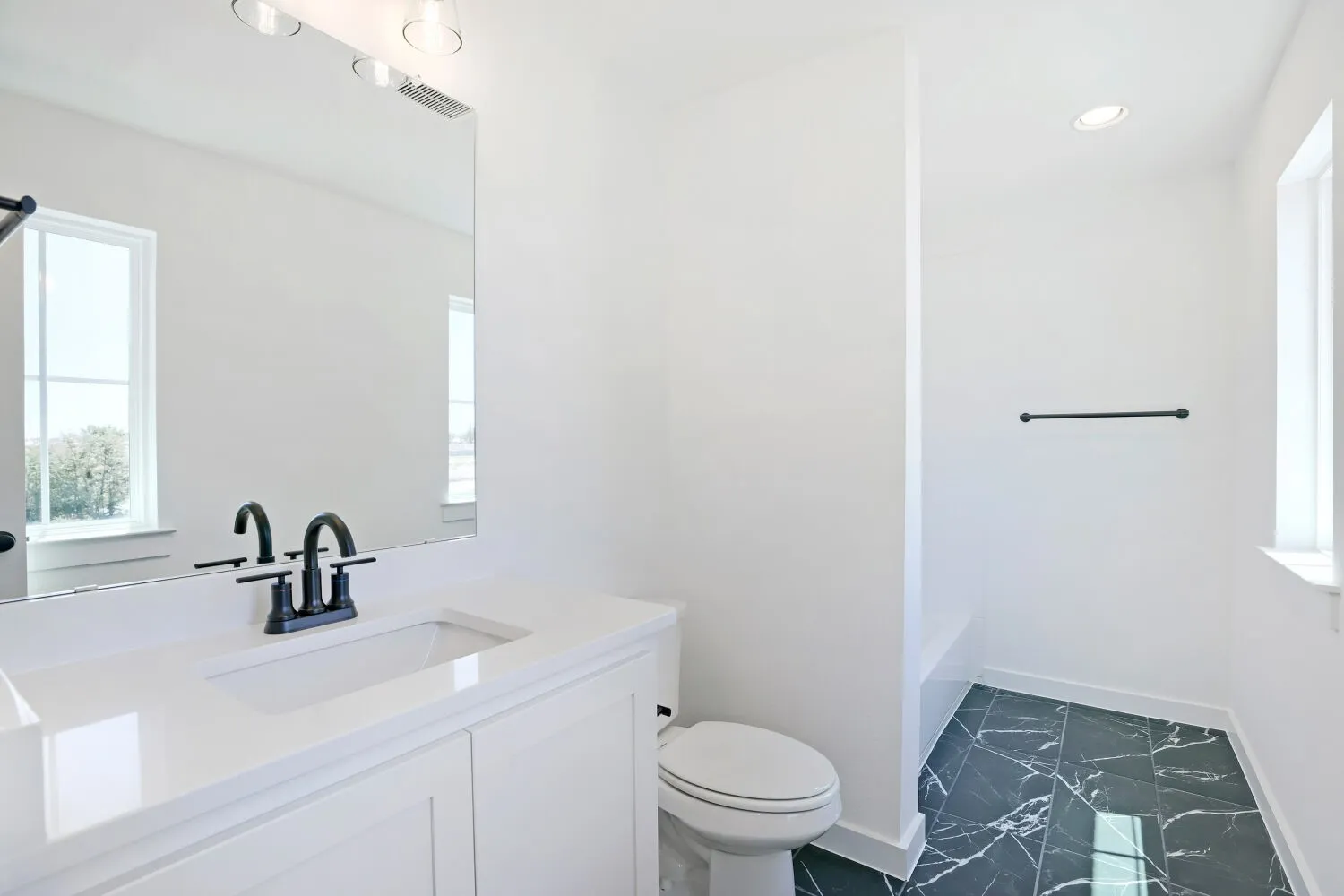 Vanity with a white countertop and integrated sink, matte black faucet, and rectangular mirror