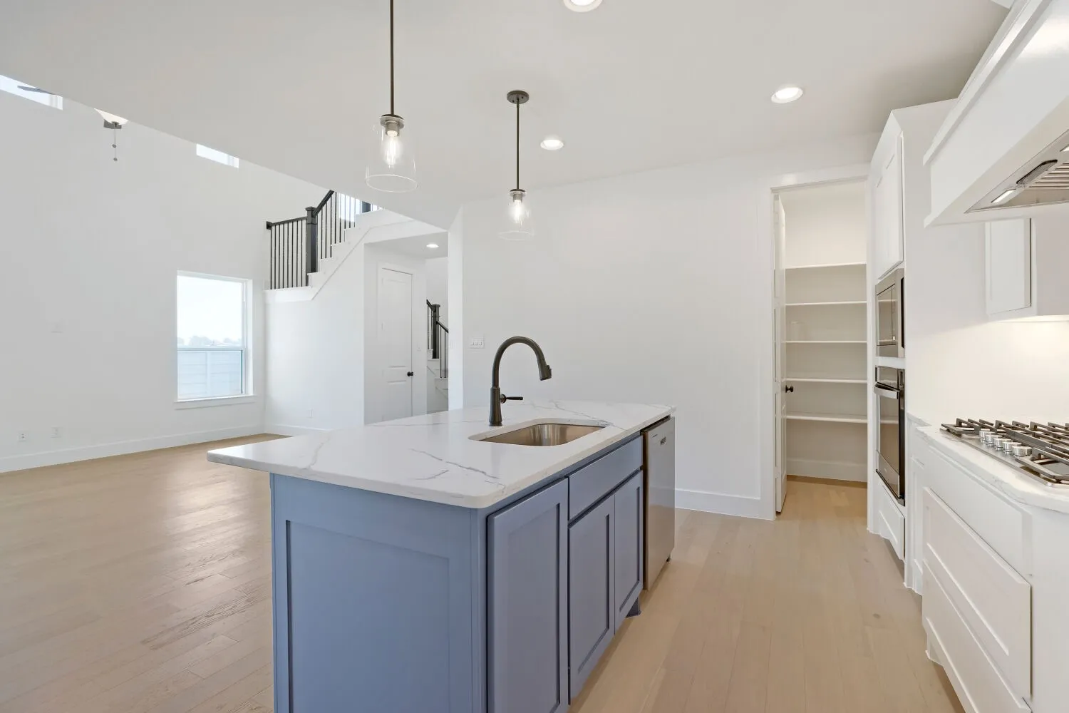 Kitchen island with light blue cabinetry, integrated sink, and quartz countertop
