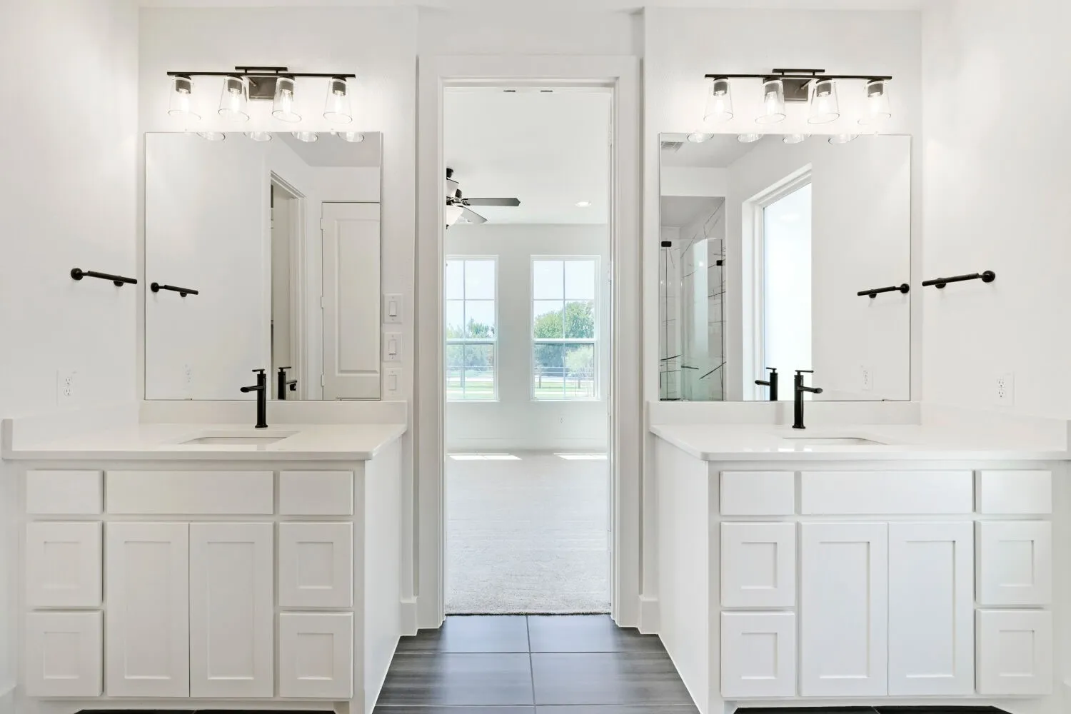 Dual white vanities with integrated sinks and matte black fixtures, under-mounted mirrors, and black-finish overhead lighting